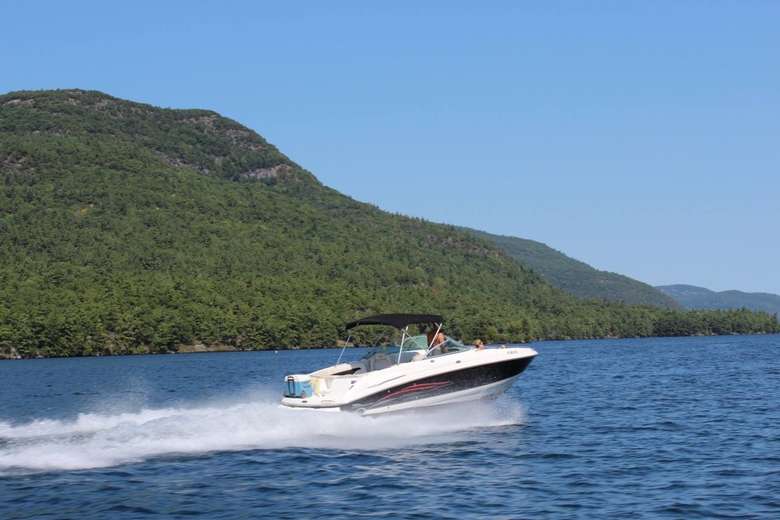 a large motorboat zooming across the waters of Lake George