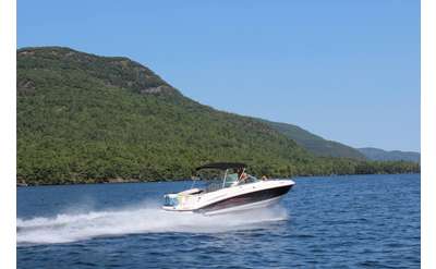 a large motorboat zooming across the waters of Lake George
