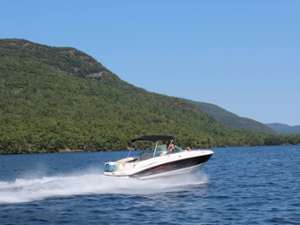 a large motorboat zooming across the waters of Lake George