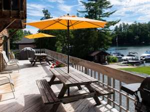 a deck with chairs and tables facing the lake