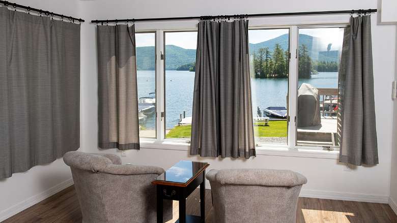 a living room area with two chairs facing large windows with a view of the lake