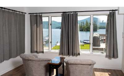 a living room area with two chairs facing large windows with a view of the lake