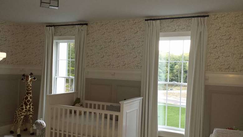 a baby's room with a crib and windows with curtains