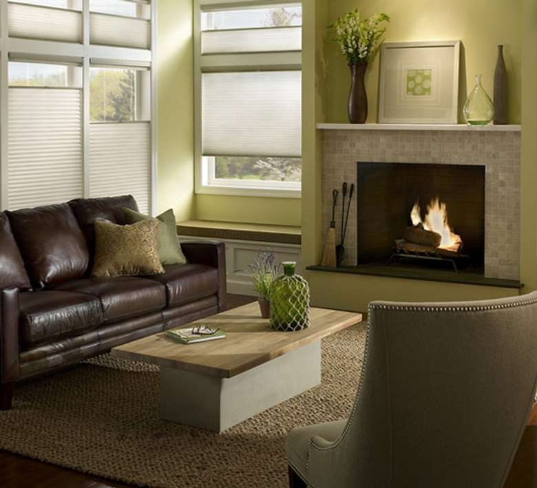 a living room with a brown leather couch, a chair, a table, and a fireplace