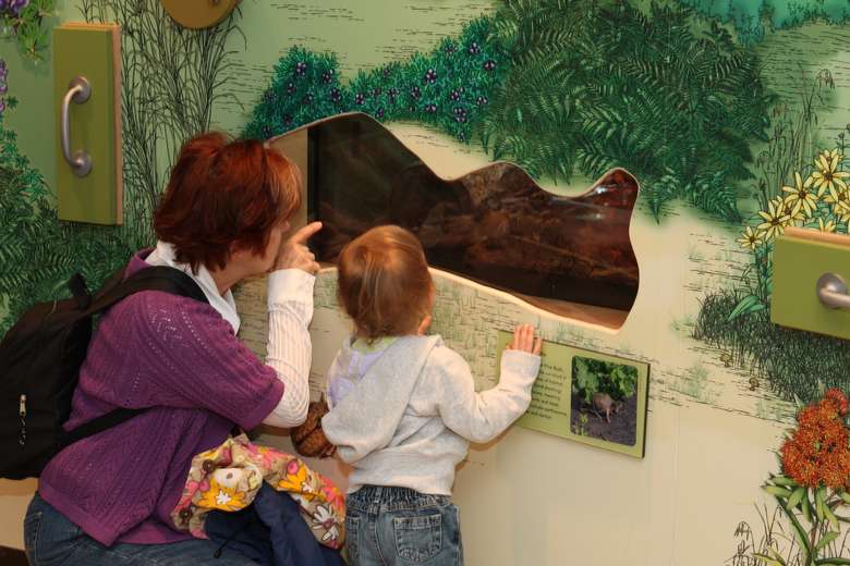 a woman and a child looking at an image on a museum wall