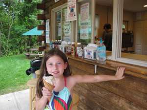 a little girl poses in front of the snack stand with an ice cream cone