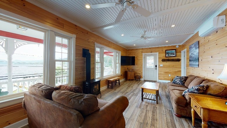 Spacious living room with a brown couch and loveseat, a lake view can be seen from the windows.