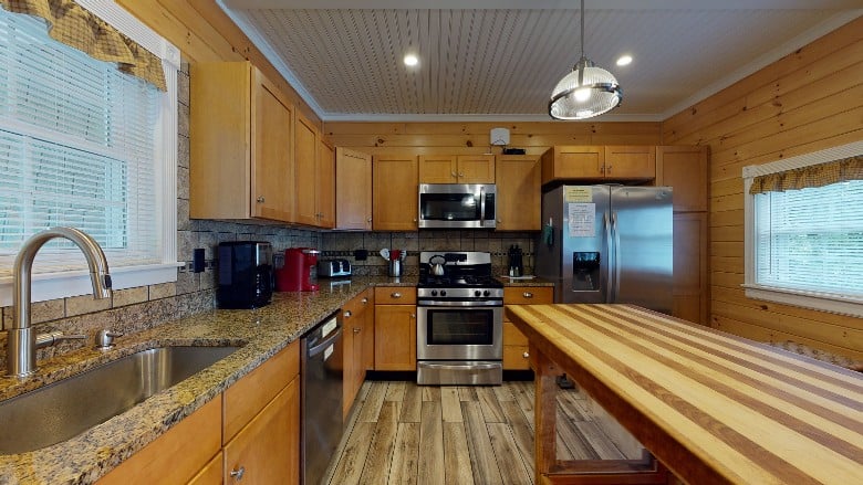 Kitchen with stainless steel refridgerator and stove. An island is in the middle of the room and the coffee makers and toaster are visible on the counter.