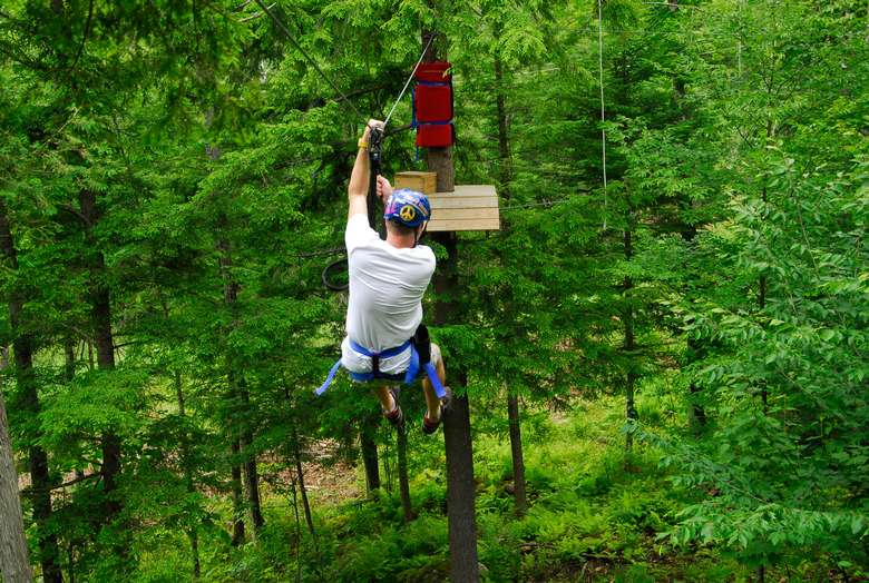 a man on a zipline in the trees