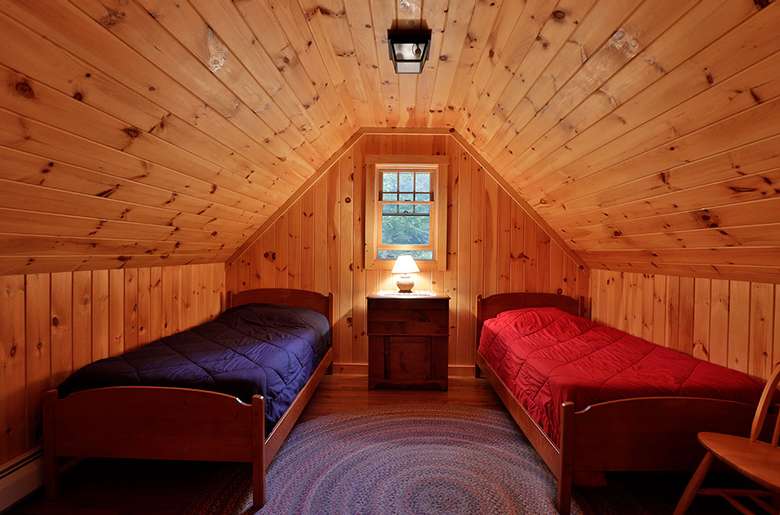 two twin beds each with a blue and a red comforter, wood paneling, low ceiling