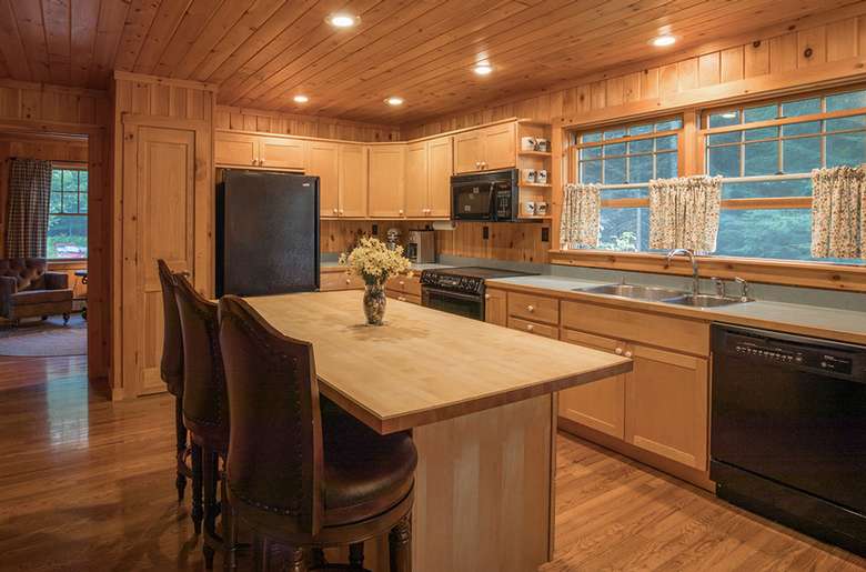 a kitchen with all wood paneling and cabinets, an island table in the middle
