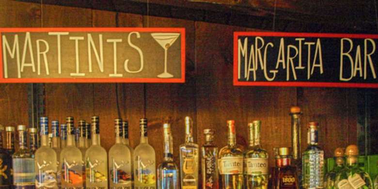 two signs for martinis and a margarita bar with bottles below