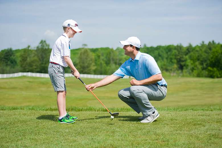 a man showing a little boy how to golf