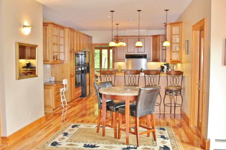 a large kitchen with wooden cabinets and flooring, a counter, fridge, and more
