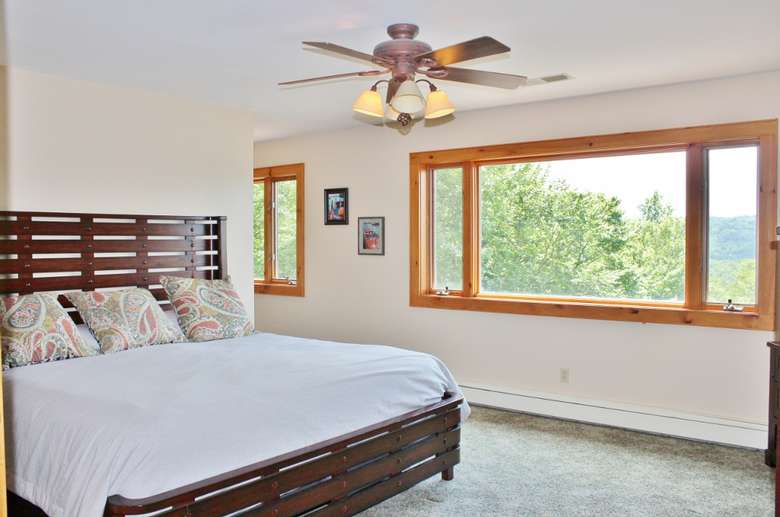 a bedroom with wide windows and a ceiling fan