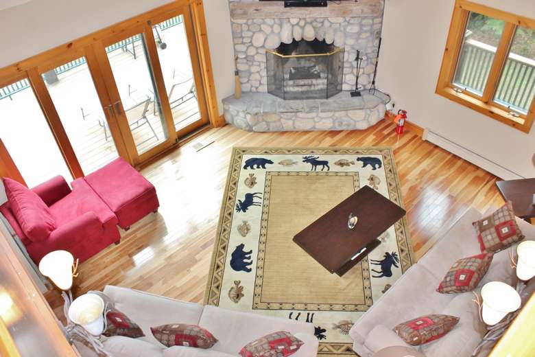 an aerial view of a living area with an adirondack themed carpet, couches, and a stone fireplace