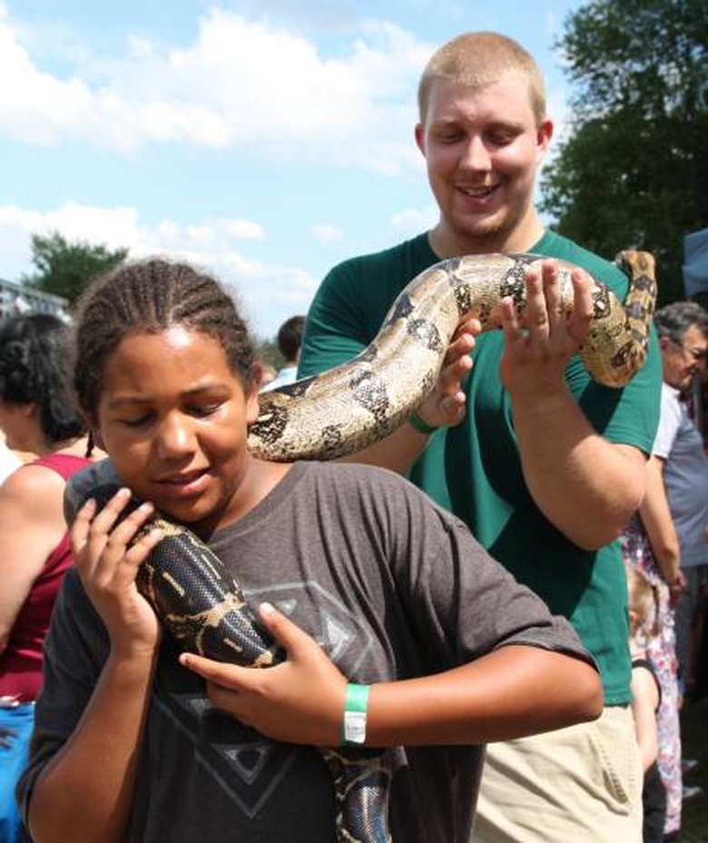 man and young girl holding large snake together