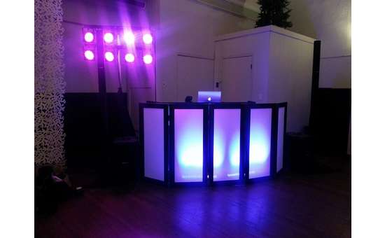 a dj booth with bright purple lights in the back