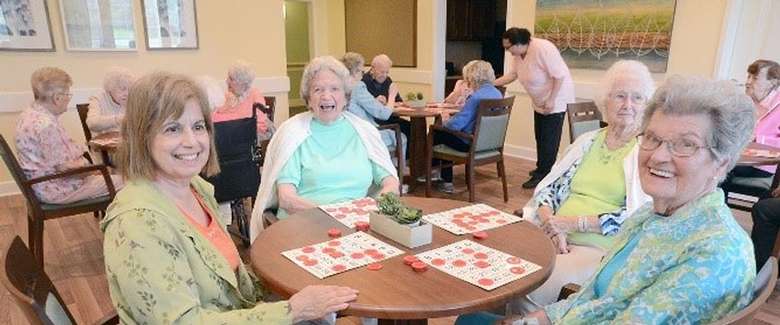 smiling elderly women sitting around a table
