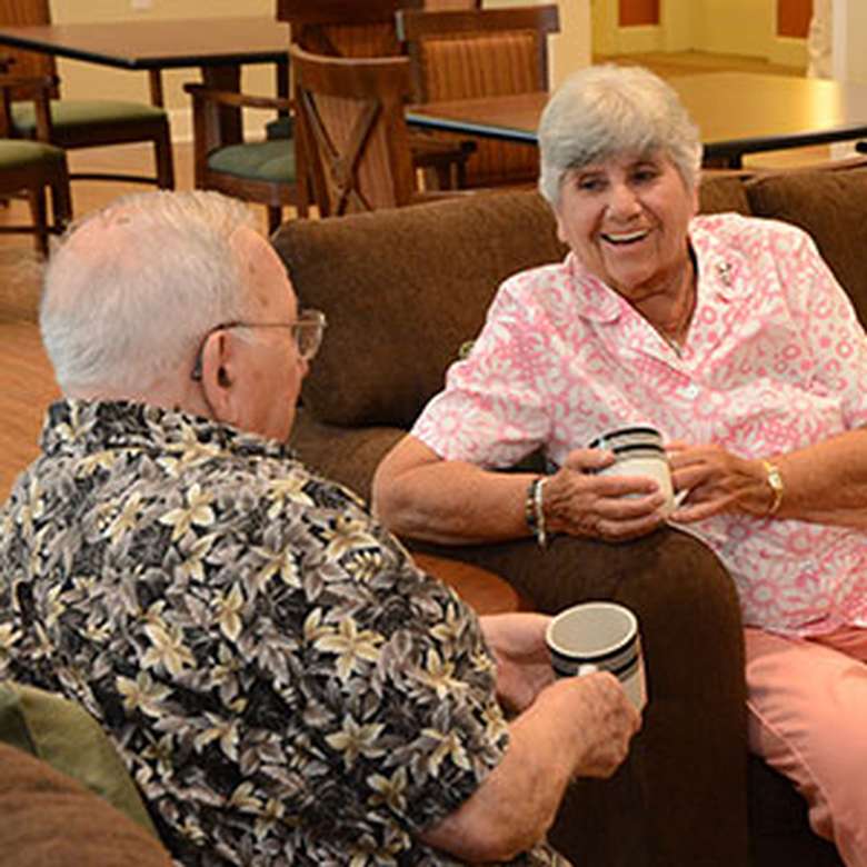 an elderly man and woman smiling over coffee