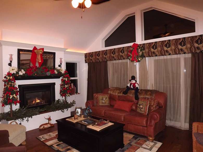 a living room that is decorated for the holidays, there is a red couch and a fireplace in it