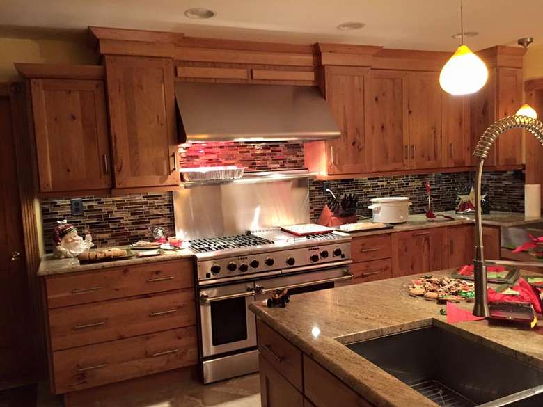 a kitchen with wooden cabinets, lights on the ceiling, and an oven