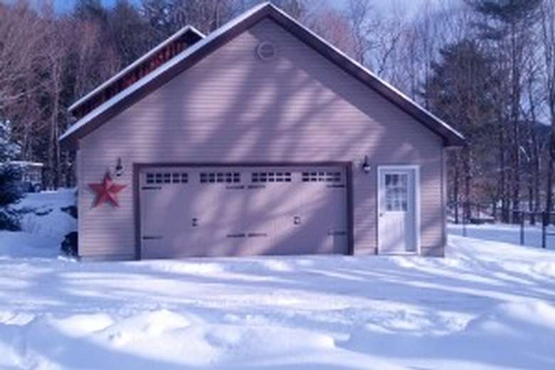 during winter with snow on the ground, there is a garage with a large front door