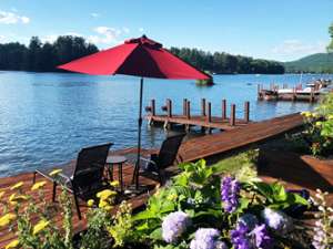 two chairs under a red and black umbrella overlooking lake george