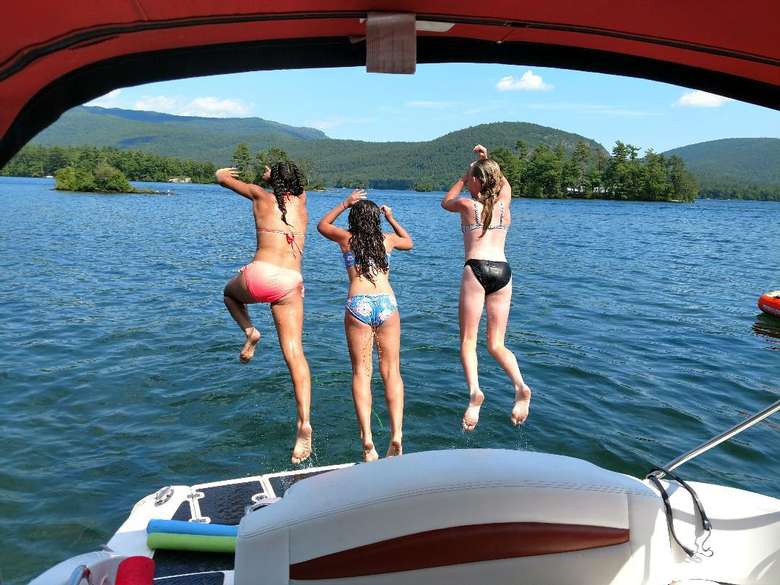 three girls jumping off the back of a boat