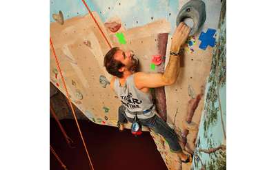 man reaching up on rock climbing wall