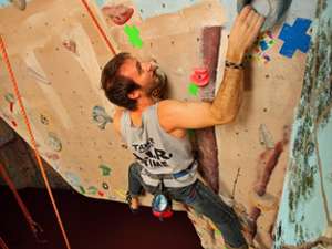 man reaching up on rock climbing wall