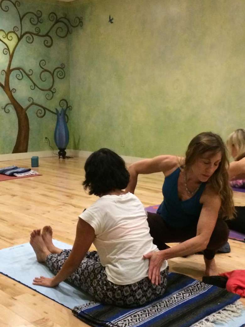 a woman helping another woman practice yoga