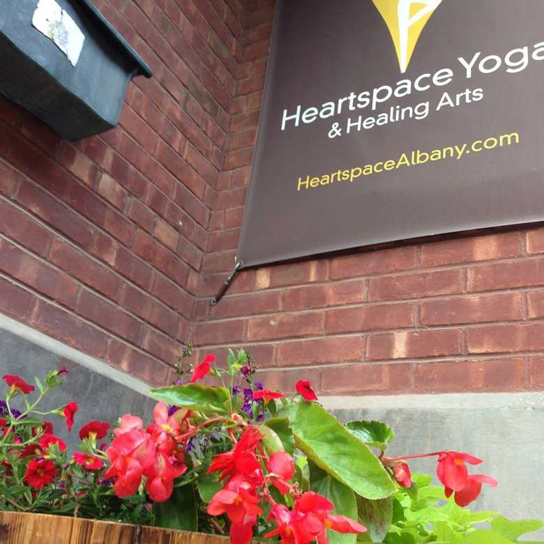 Heartspace Yoga sign on the outside of a building with a plant