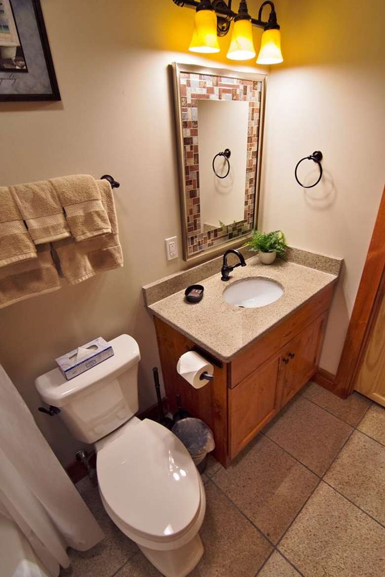 a bathroom with a toilet next to the sink and cabinet