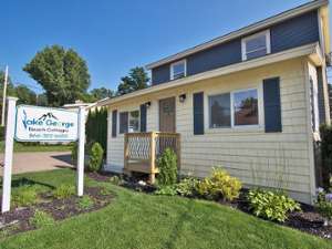 the exterior of a house with the lake george beach cottages sign nearby