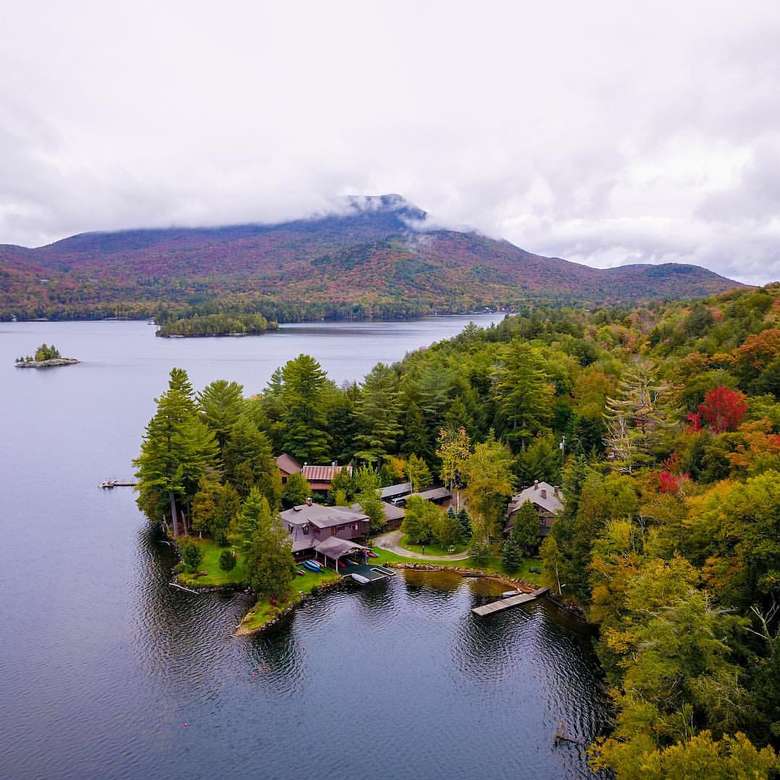 an aerial view of rustic lodges in the woods on the waterfront