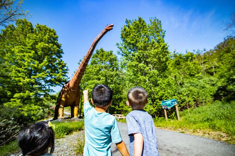two boys looking up at a dinosaur
