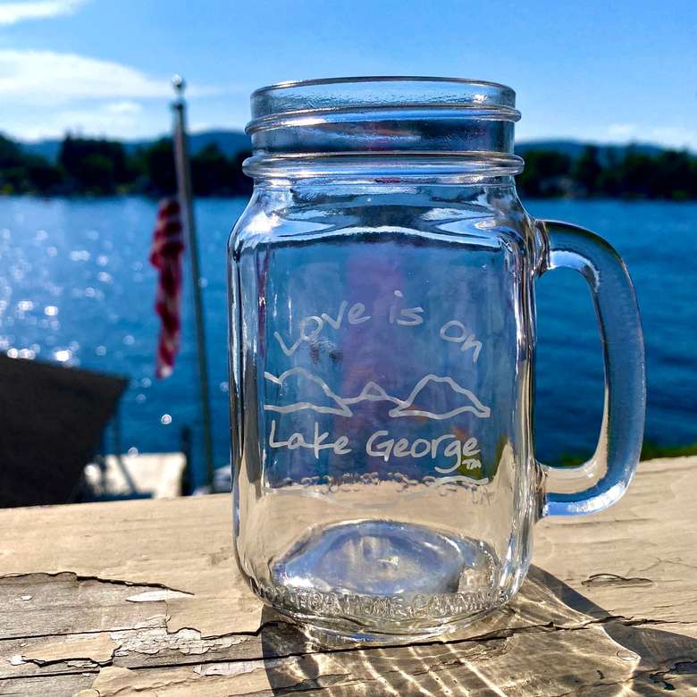 Love is on Lake George text over our custom mountain and lake scene on a clear glass handled mason jar