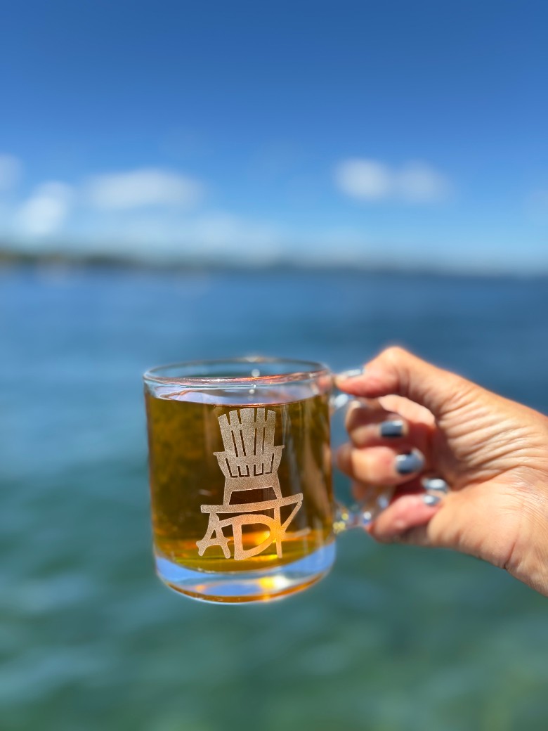 ADK under an Adirondack Chair hand sand blasted on a clear glass coffee mug