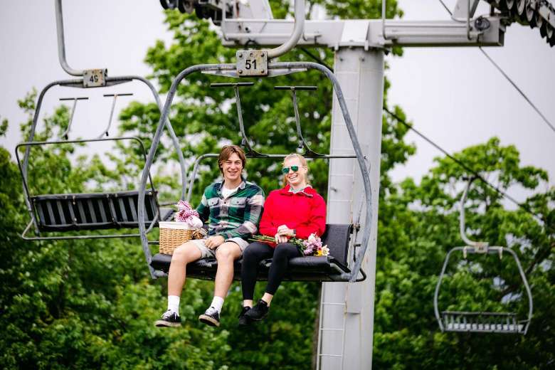 man and woman riding up a chairlift