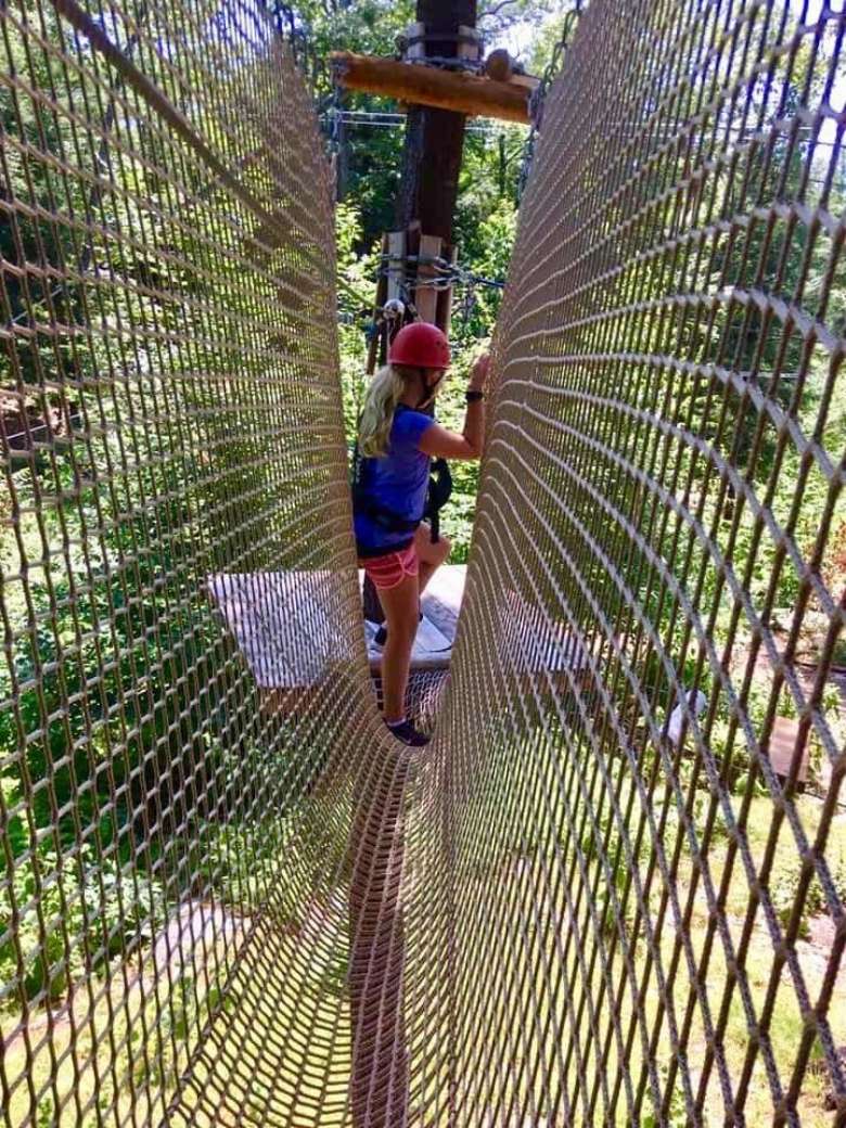 a woman moving through rope net obstacle in the trees