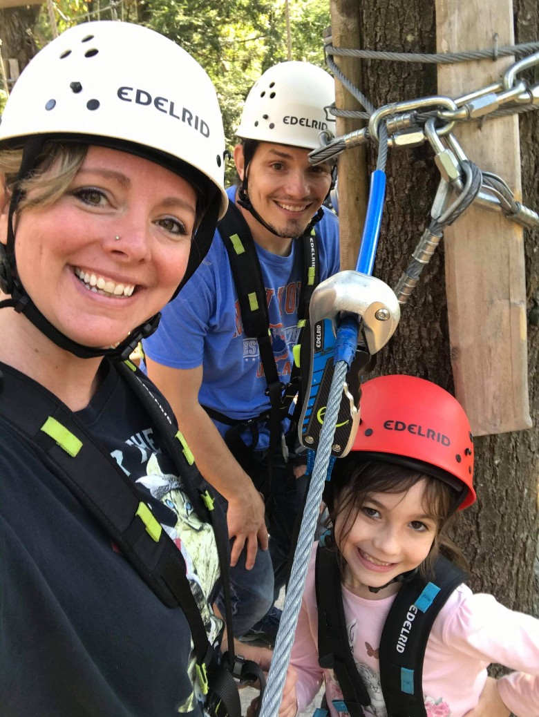 man, woman, and young girl on aerial adventure park
