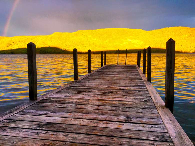 wooden dock and yellow sunset shining on mountains