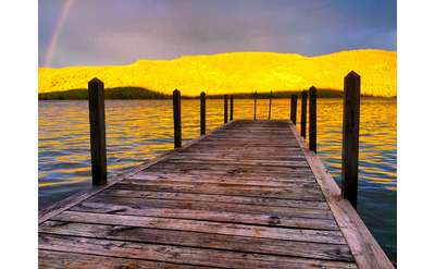 wooden dock and yellow sunset shining on mountains