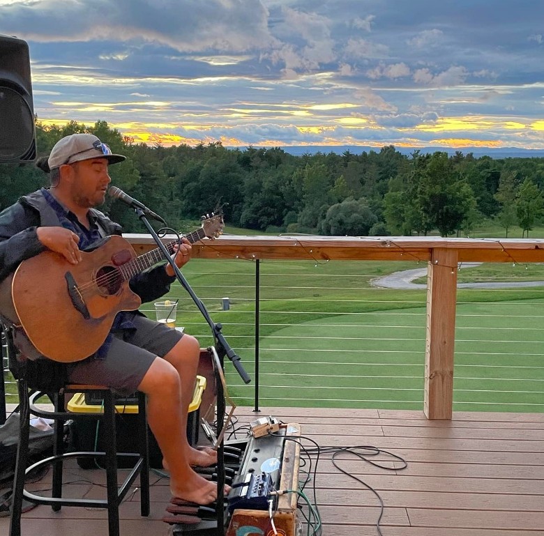 man playing guitar on a patio