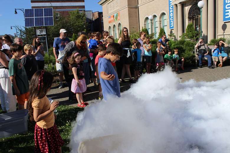 group of people outdoors with a smoke filled science experiment