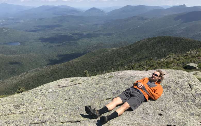 hiker laying on rocky summit