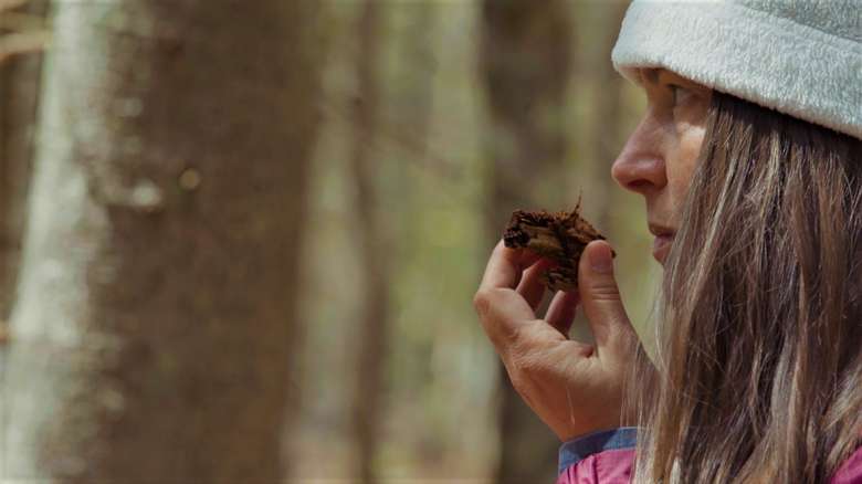 woman smelling a piece of bark