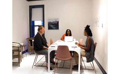 three women sitting around a coworking table