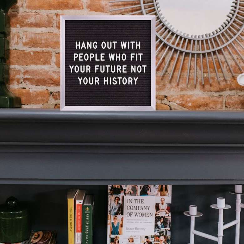 bookcase with sign that reads Hang Out With People Who Fit Your Future Not Your History